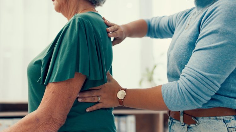 Physiotherapeut untersucht den Rücken einer Seniorin