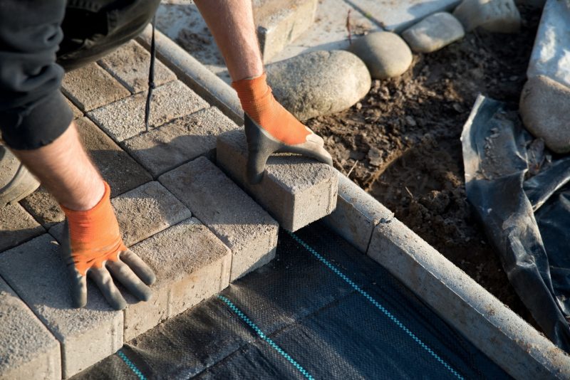 Handwerker legt Gartenweg mit Pflastersteinen an